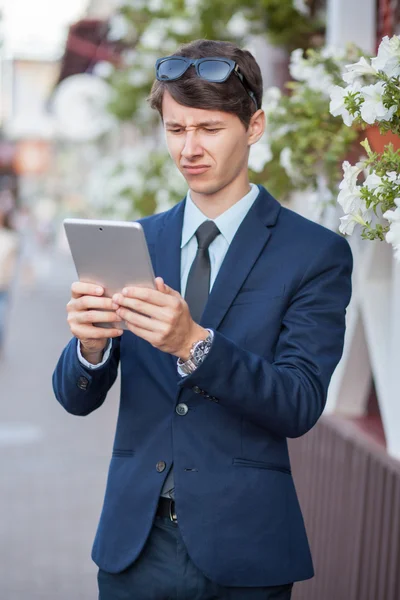 Szczęśliwy młody biznesmen przy pomocy i pracy na tablet Pc na ulicy miasta, przy użyciu bezprzewodowego dostępu do Internetu w pobliżu café. — Zdjęcie stockowe