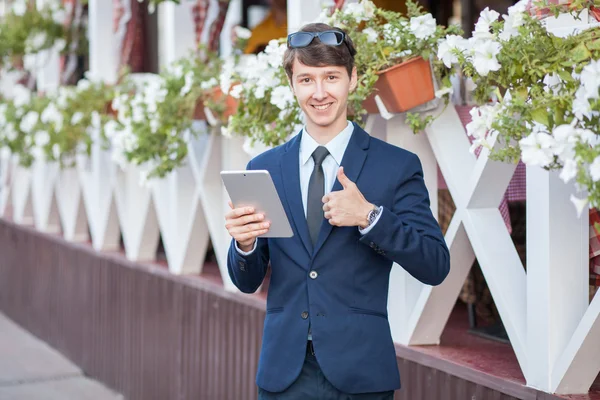 Szczęśliwy młody biznesmen przy pomocy i pracy na tablet Pc na ulicy miasta, przy użyciu bezprzewodowego dostępu do Internetu w pobliżu café. — Zdjęcie stockowe