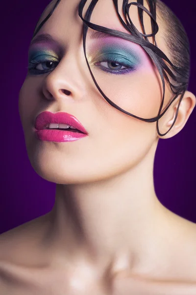 Giovane bella modella di moda con trucco rosa e blu e acconciatura sul suo viso. sfondo viola. studio girato . — Foto Stock