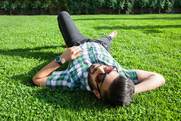 Одна мода середній східний чоловік з бородою, стиль модного волосся відпочиває на красивому зеленому трав'яному денному часі. молодий арабський бізнесмен 20-30 років, відпочиває після важкої роботи. смартфон, планшет . — стокове фото