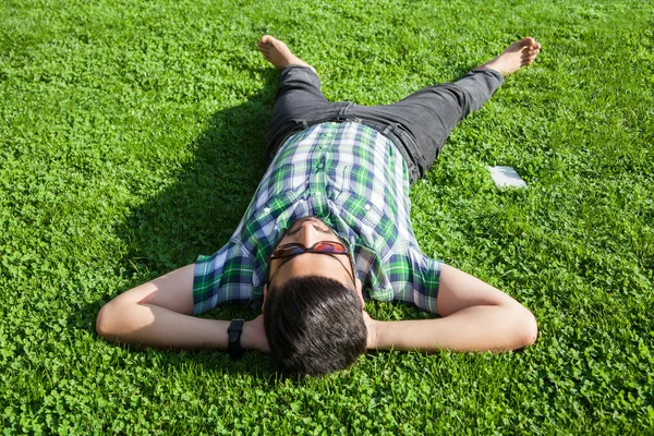 Un hombre de moda de Oriente Medio con barba, estilo de pelo de moda está descansando en el hermoso tiempo de día de hierba verde. joven hombre de negocios árabe 20-30 años, descansando después del trabajo duro. teléfono inteligente, tableta . —  Fotos de Stock