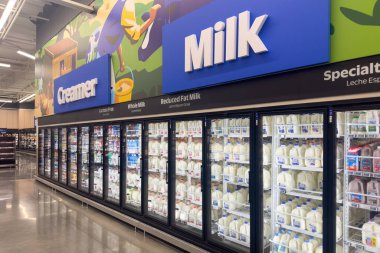 Frisco, Texas, ABD - 12 Eylül 2025: Cam kapılı soğutucularda süt tabelaları ve sıra sıra süt ürünleri bulunan dondurulmuş süt ürünleri koridoru