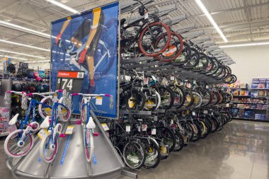 Frisco, Teksas, ABD - 12 Eylül 2025: Rampalarda sıralanmış yetişkin ve dağ bisikletleri, yerde renkli çocuk bisikletleri ve flamalar ve kasklar bulunan bisiklet bölümleri