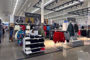 Frisco, Teksas, ABD - 12 Eylül 2025: Geniş Walmart giyim bölümünde raflarda ve mankenlerde reklam tabelaları ve katlanmış ürünler yer alıyor