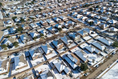 Frisco, Teksas, ABD - 3 Ocak 2024: Açık kış gökyüzü altında çatılar, bahçeler ve caddeler üzerinde taze karla kaplı tek aile evleri olan insansız hava aracı yerleşim banliyösü manzarası