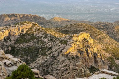 Lemmon Dağı 'nın kayalık tepelerinden altın günbatımı manzarası katmanlı taş oluşumlarını gösteriyor dağılmış çalılıkları ve dramatik bulutlu gökyüzünün altındaki vadileri.