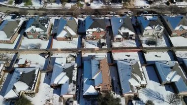Frisco, Teksas, ABD - 3 Ocak 2024: Karla kaplı çatıları, arka bahçeleri ve park halindeki arabaları olan banliyö evlerinin insansız hava aracı görüntüsü