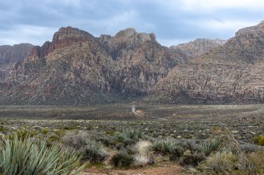 Las Vegas, Nevada, ABD - 1 Mart 2024 Büyük dağlara doğru uzanan uzun düz yol Red Rock Kanyon Çölü manzarası