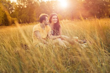 Loving couple lying down on floral field in autumnal park, warm sunny day, enjoying family, romantic date, happiness and love concept. happiness and smile.