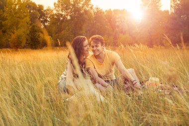 Loving couple lying down on floral field in autumnal park, warm sunny day, enjoying family, romantic date, happiness and love concept. happiness and smile.