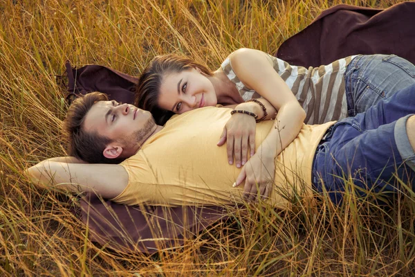 Loving couple lying down on floral field in autumnal park. enjoy, relax and r — Stock Photo, Image