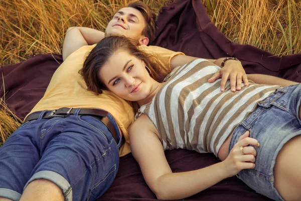 Pareja cariñosa acostada en el campo floral en el parque otoñal. disfrutar, relajarse y r — Foto de Stock