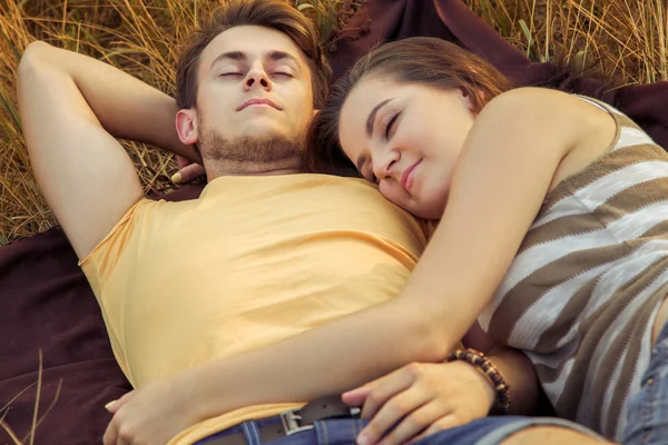 Loving couple lying down on floral field in autumnal park, warm sunny day, enjoying family, romantic date, happiness and love concept. relaxing and rest with closed eyes. sleep. — Stock Photo, Image