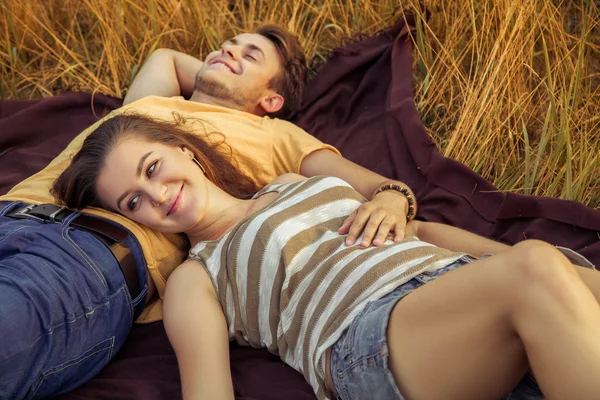 Loving couple lying down on floral field in autumnal park. enjoy, relax and r — Stock Photo, Image