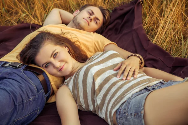 Pareja cariñosa acostada en el campo floral en el parque otoñal, cálido día soleado, disfrutando de la familia, cita romántica, la felicidad y el concepto de amor. mirando a la cámara con sonrisa . — Foto de Stock