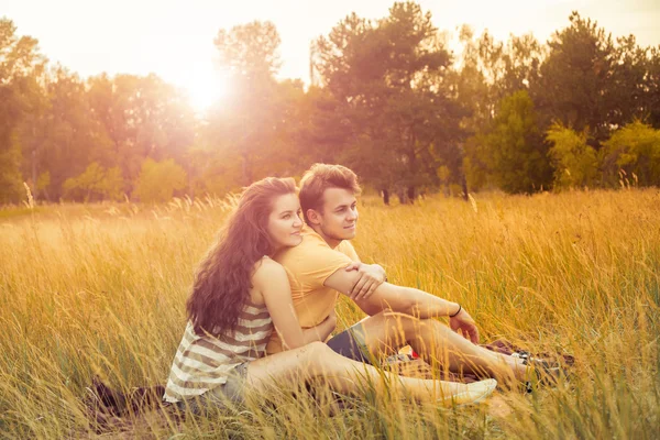 Loving couple lying down on floral field in autumnal park, warm sunny day, enjoying family, romantic date, happiness and love concept. hug and side looking. — Stockfoto