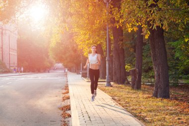genç güzel mutlu ve seksi atlet sonbahar renkli parkta güzel bir vücut kızla. arka ışık tarih Pzr ile kameraya mutluluk ve gülümseme ile beyaz spor takım elbise ile bakıyor.