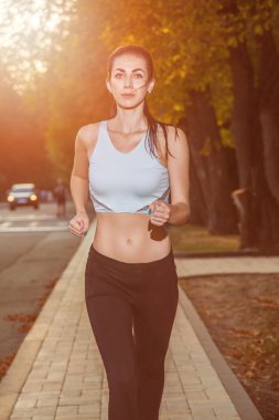 genç güzel mutlu ve seksi atlet sonbahar renkli parkta güzel bir vücut kızla. arka ışık tarih Pzr ile kameraya mutluluk ve gülümseme ile beyaz spor takım elbise ile bakıyor.