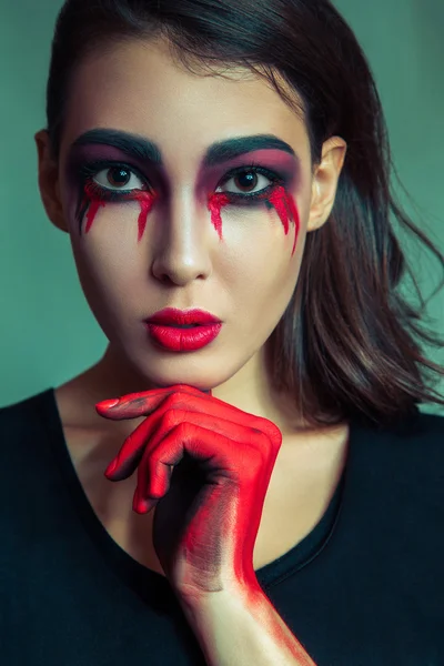 Portret potwór freak bałagan brudnych kolorowy makijaż na twarzy. Płacząca kobieta z czerwonym krwawe łzy i ręcznie. Halloween koncepcja na zielonym tle. cukinia, ciemnobrązowe oczy. — Zdjęcie stockowe