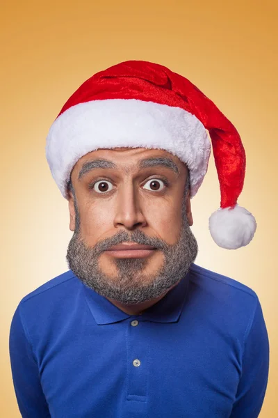 A caricatura colorida da cláusula engraçada do Papai Noel com cabeça grande e camisa azul, chapéu vermelho com barba cinza, surpreso olhando para a câmera no fundo laranja — Fotografia de Stock