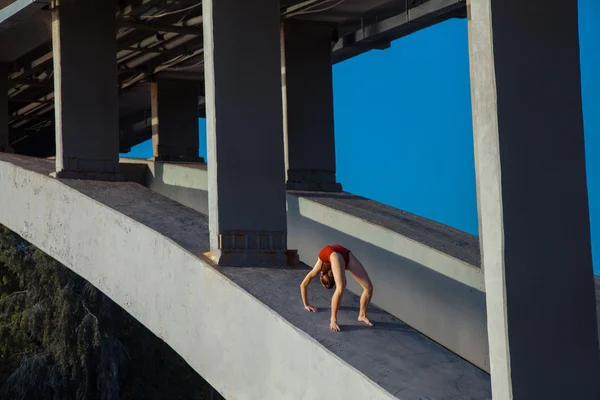 Young beautiful woman gymnast posing on bridge girder — Stok fotoğraf