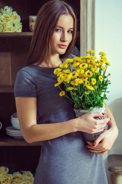 Hermosa joven modelo de moda sosteniendo flores amarillas . —  Fotos de Stock