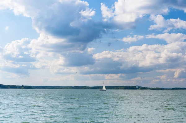 Lake under sky with clouds and sailboat — Stock Photo, Image