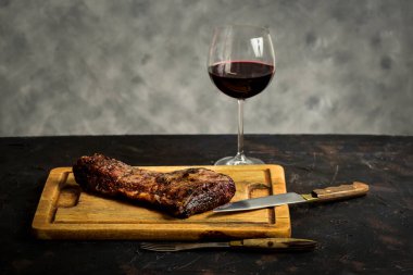 Roasted beef ribs with a glass of red wine presented on the table, traditional Argentine cuisine, Asado barbecue, Patagonia, Argentina. clipart