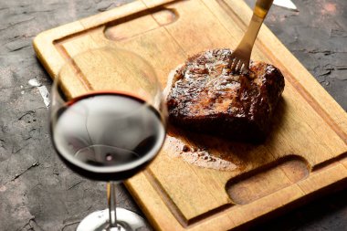 Masada bir bardak kırmızı şarapla ızgara biftek, geleneksel Arjantin mutfağı, Asado barbeküsü, Patagonya, Arjantin.