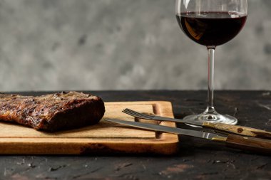 Masada bir bardak kırmızı şarapla ızgara biftek, geleneksel Arjantin mutfağı, Asado barbeküsü, Patagonya, Arjantin.