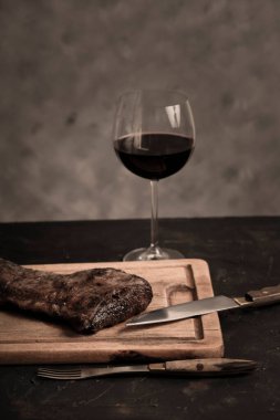 Masada bir bardak kırmızı şarapla ızgara biftek, geleneksel Arjantin mutfağı, Asado barbeküsü, Patagonya, Arjantin.