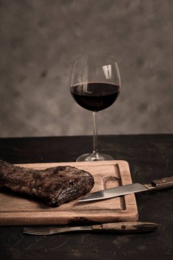Roasted beef ribs with a glass of red wine presented on the table, traditional Argentine cuisine, Asado barbecue, Patagonia, Argentina. clipart
