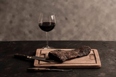Masada bir bardak kırmızı şarapla ızgara biftek, geleneksel Arjantin mutfağı, Asado barbeküsü, Patagonya, Arjantin.
