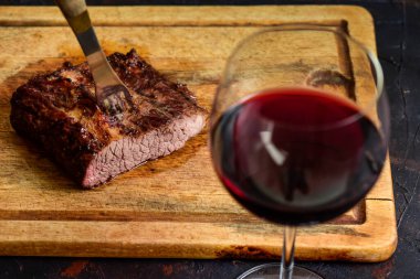 Masada bir bardak kırmızı şarapla ızgara biftek, geleneksel Arjantin mutfağı, Asado barbeküsü, Patagonya, Arjantin.