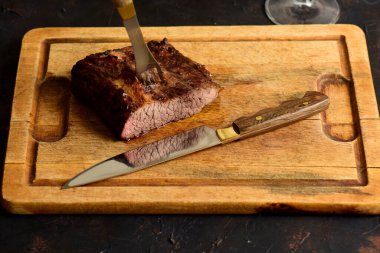 Masada bir bardak kırmızı şarapla ızgara biftek, geleneksel Arjantin mutfağı, Asado barbeküsü, Patagonya, Arjantin.