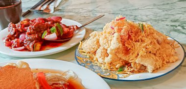 Bir tabak kızarmış tavuk altın renginde tereyağı kırıntılarıyla kaplanmış soğan ve biberli baharatlı kızartma tabağının yanında duruyor. 