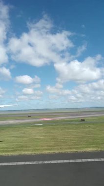 Malezya, Kuala Lumpur 01.01.2025 uçak penceresinden havalimanı pistinin dikey portre görüntüsü, bulutlu gökyüzü, taksi işaretleri ve KLIA 'dan kalkan hareket halindeki yer araçları ve hava araçları