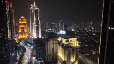 Gece boyunca modern yüksek binalar ve daha eski, düşük yoğunluklu yerleşim ve ticari alanların karışımının hakim olduğu büyük, yoğun bir metropol şehrinin hızlandırılmış çekimi