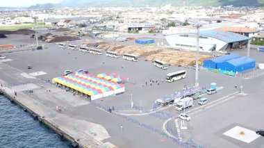 Gemileri, vinçleri, konteynırları ve okyanus suyunu gösteren büyük bir kargo limanı sahnesi.