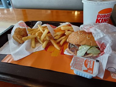 Auckland, Yeni Zelanda, 1 Ocak 2026 bir fast food tepsisi Burger King restoranında servis edilen hamburger kızartması sosu ve meşrubatları gösteriyor.
