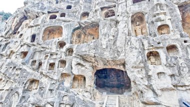 Kapsamlı Longmen mağaraları dramatik kireçtaşı kaya yüzeyinde yüzlerce oyulmuş Budist oyma oyma oyma oyma oymaları ve heykeller sergiliyor.