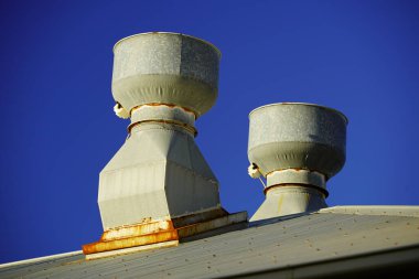 Çatıya monte edilmiş egzoz vantilatörleri tavanda mavi gökyüzü arka planda