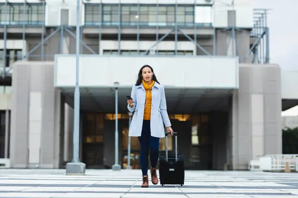 Asyalı Bir Kadın Akıllı Telefon Tutuyor Elinde Bavulla Sokakta Yürüyor — Stok fotoğraf
