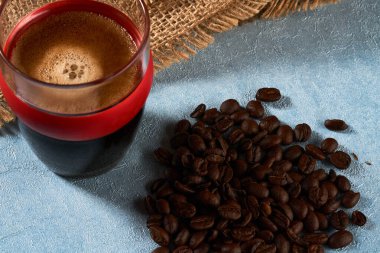                                 Küçük bir bardak sade kahve, kahve çekirdeği ve çuval bezi.