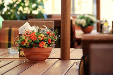 Restorandaki bir masada saksıda güzel çiçekler var..