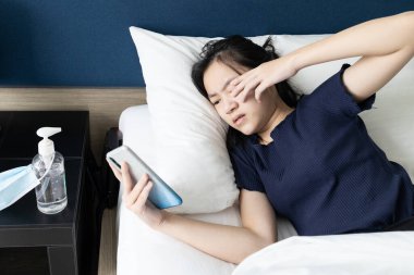 Uzun süre cep telefonu kullanan Asyalı kız, gözlerini ovuşturur, kaşınır, gözleri yanar ve tahriş olur ya da gözlerini ovuşturma, Coronavirus COVID-19 salgını sırasında kirli ellerle yüzüne ve burnuna dokunma.