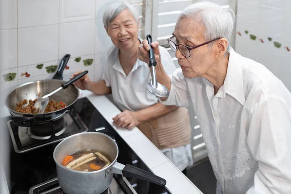 亚洲老年人做饭 品尝蔬菜汤 老年人在厨房享用泰国菜 健康食品 好厨师 味道鲜美 — 图库照片