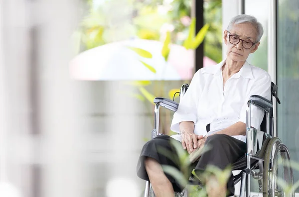 悲しいと落ち込んでアジアの高齢者の女性だけで車椅子に座って頭を下げて孤独と退屈を感じます 彼女の家族が老人ホームで彼女を訪問するのを待っている孤独と障害者の高齢者 — ストック写真