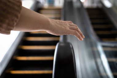 Avoid and Don't touch with objects that are frequently touched for safety,hand of girl was about to touch the handrail of escalator at risk of Coronavirus infection,contaminated with germs or COVID-19 clipart