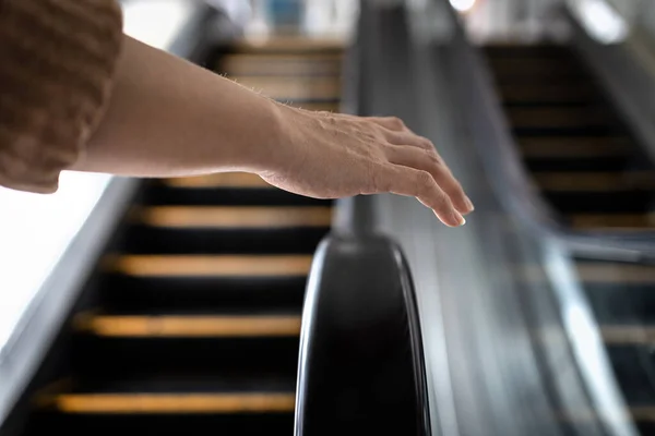 Avoid and Don\'t touch with objects that are frequently touched for safety,hand of girl was about to touch the handrail of escalator at risk of Coronavirus infection,contaminated with germs or COVID-19